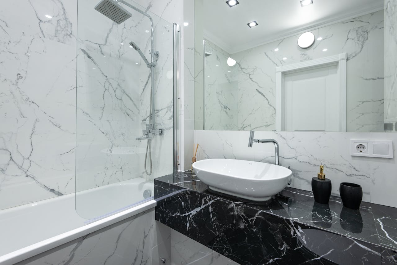 Luxurious bathroom featuring marble walls, a vessel sink, and contemporary fixtures.